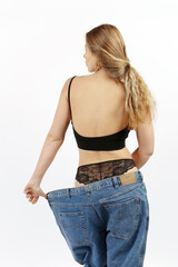 Slim girl in oversized pants shows the result of losing weight. Diet, nutrition and exercise