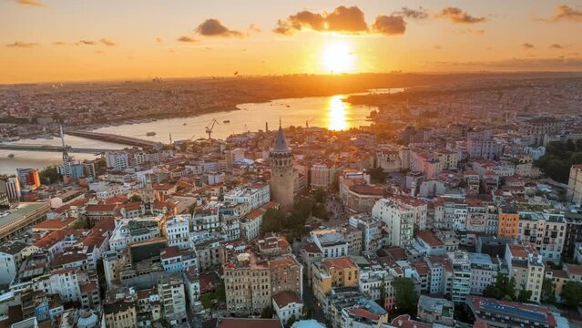 Aerial drone hyperlapse view of Istanbul at sunset, Turkey. Multiple residential buildings around the Galata tower, nightlights, Golden Horn waterway on the background