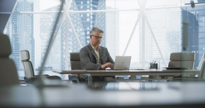 Portrait of Successful Caucasian Businessman Working on Laptop Computer in His Big City Corner Office. Professional Male Digital Entrepreneur does Data Analysis for e-Commerce Strategy Assessment.