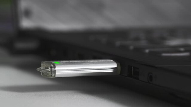 young woman inserts a flash drive into a usb port into a computer on table, close-up