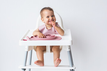 baby smiling sits in a high chair in full growth eats complementary foods on a white background