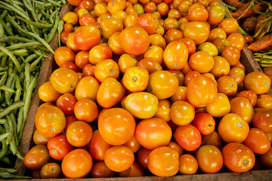 Fresh tomatoes and green beans on display at a farmers market stall.