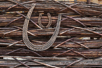 On a fence weaving from twigs there is an old rusty horseshoe, a symbol of good luck and happiness.