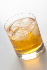 Crystal glass with whiskey and ice cubes on white background
