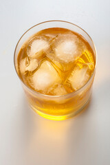 Crystal glass with whiskey and ice cubes on white background
