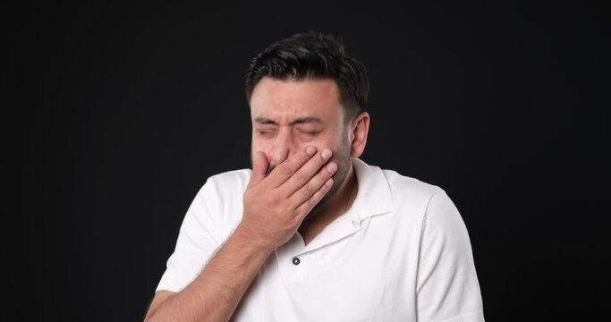 The when a middle-aged man in a studio setting, through close-up shots, looks at the camera and makes gestures and facial expressions that indicate being extremely ill