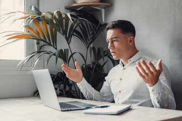 Unhappy young caucasian male worker in glasses look at laptop screen shocked by gadget breakdown or...