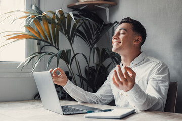 Serene office male employee sit at desk relaxing doing yoga, practice meditation to reduce stress...