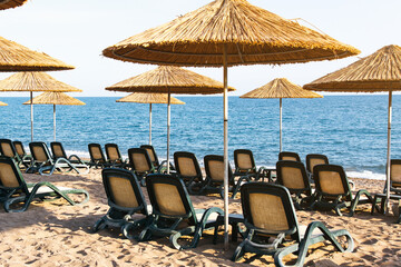 empty sandy beach with sun loungers and a canopy, beautiful blue calm sea