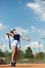 Fototapeta na wymiar Full-length dynamic image of young athletic woman, tennis player in uniform during game, playing at open air stadium, court on warm day. Concept of sport, hobby, active lifestyle, health, strength, ad