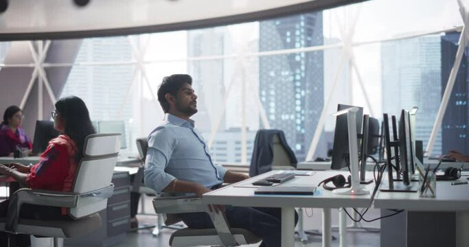 Group of Multicultural South Asian Men and Women Working in a Research Center, Collaborating on a Corporate Project. Indian Man Focused on a Task is Using Computer to Analyze Business Opportunities