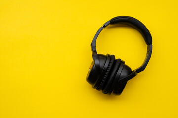 Fototapeta na wymiar Wireless headphones in black on a yellow background.
