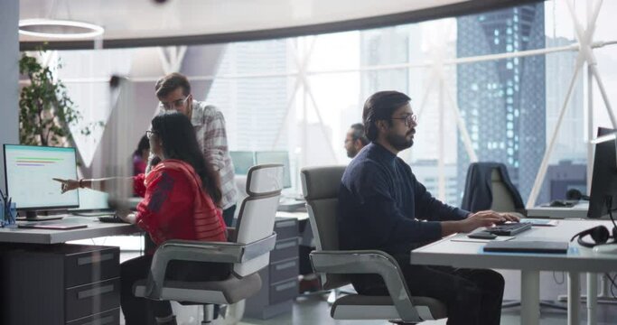 Young Team of Indian Specialists Working on Computers and Having a Conversation in the Office. Male and Female Colleagues Discussing a Solution for Their Generative Artificial Intelligence Project