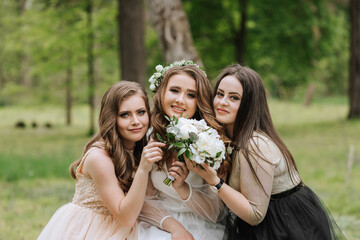 Wedding walk in the forest. Brides and their friends pose against the background of the forest. A large group of people are having fun at their friends' wedding