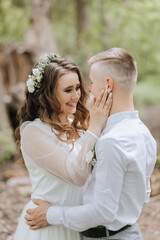 Wedding walk in the forest. The bride and groom look at each other. Portrait of a couple in love in...