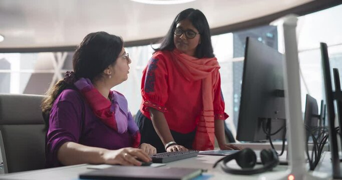 Two Beautiful Indian Women Working in a Business Software Development Department in a Bank. Specialists Having a Conversation About Financial Year Results, Reporting and Marketing Campaign Results