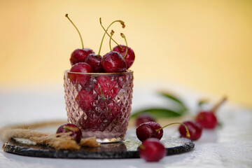 Frische rote knackige Kirschen auf dem Tisch im Glas  - 621891349