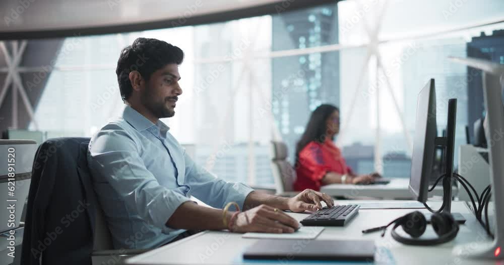Poster portrait of an indian businessman working on a desktop computer in a fintech startup company. south 