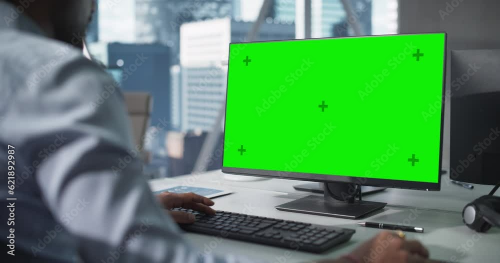 Poster over the shoulder footage of a close up computer screen with green mock up template. anonymous man w