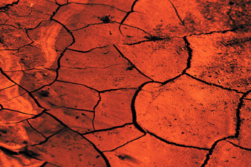 A cracked clay road dried up after a flood. Red evening sunset, twilight. The drought has come....