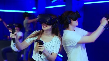 Two teenagers in virtual reality glasses with joysticks play survival game in stone jungle of future. High quality 4k footage