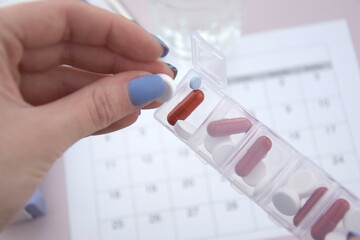 Calendar with pills and non-contact thermometer on light background.