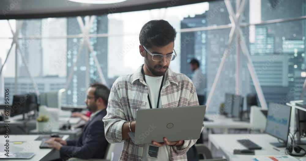 Leinwandbilder Professional Indian Specialist Using Laptop while Standing in an Office Near a Window with a Big City View. Successful Software Data Engineer Optimizing Corporate Database, Update Security Network