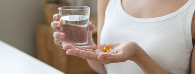 Nourishing the Body, Embracing Wellness: A Person Taking Fish Oil Supplements for Optimal Health...