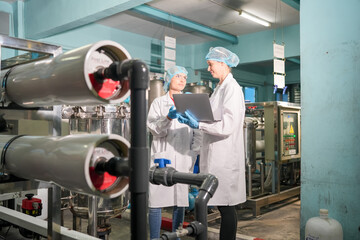 Female worker inspecting water bottle on production line in spring water factory