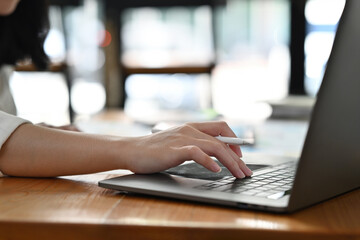 Fototapeta premium Close up and cropped image of Young businesswoman's hand typing on laptop keyboard.