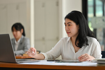 Portrait of Asian businesswoman or female office worker sit and work at her desk inside the company.