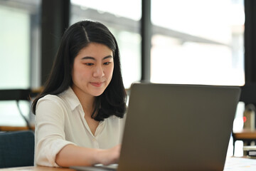 Portrait image of Young Asian businesswoman or female office worker working with laptop.