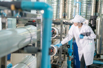 Female worker inspecting water bottle on production line in spring water factory