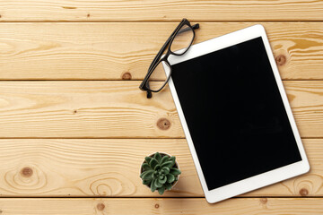 Top view of wooden table with white digital tablet with black screen on it