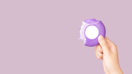 Asthma and COPD concept. Hand holding medicine dry powder inhaler on violet background. Pharmaceutical product is used to lung inflammation and prevent asthma attack. - obrazy, fototapety, plakaty