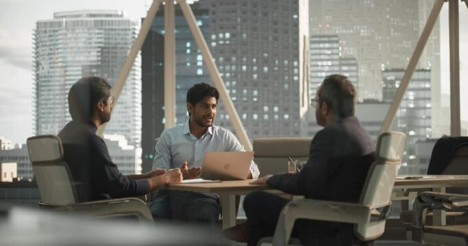 Group of Young Indian Financial Advisers Having a Conversation About a Stock Market Strategy in a Modern Industrial Office. South Asian Managers Work in a Banking Research and Development Center