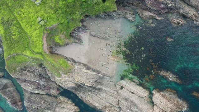 Aerial view of rocky coastline at Talland Bay with high cliffs along the coastline at sunset, Cornwall, United Kingdom.