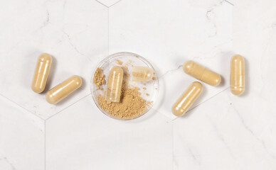Taking dietary supplements with capsules. One capsule Opened in a jar on marble table