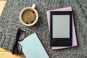 E-book reader and cup of coffee on knit plaid background
