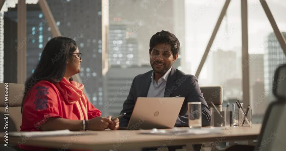 Poster two diverse indian financial advisers use laptop computer to discuss a stock market strategy in a mo