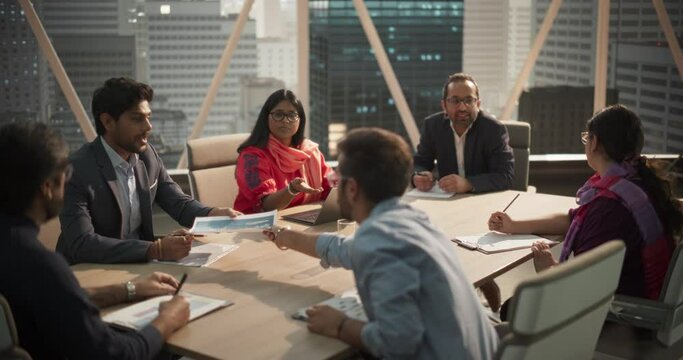 In a Modern Corporate Office Meeting Room: Diverse Group of Businesspeople, Lawyers, Executives and Members of the Board Listening to a Young Indian Female CEO Talking About Achieved Business Goals