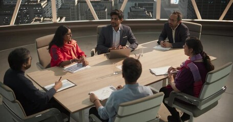 High Angle Footage of a Diverse Team of Professional South Asian Businesspeople Meeting in an Office Conference Room. Creative Team Sitting Behind a Table, Discussing Social Media Marketing Strategy - Powered by Adobe