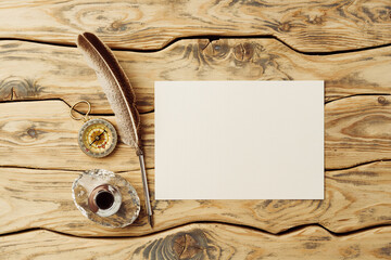 Old paper on brown wood background with feather