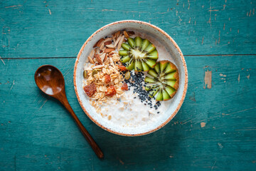 Healthy breakfast, oatmeal, kiwi and granola on green background