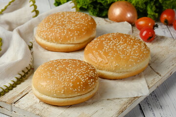 freshly baked plain golden brown hamburger buns topped with sesame seeds - Powered by Adobe
