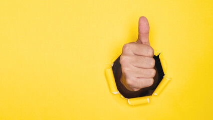 Businessman hand thumb up from yellow punched paper for client the best satisfaction evaluation...