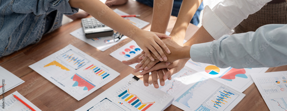 Aufkleber Analyst team putting hand together after successfully analyzed financial dashboard papers for business strategy and marketing. Teamwork and unity in office with stack hands. Panorama shot. Scrutinize