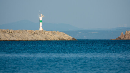 The view of the coastline and the lighthouse in the calm sea of Gökçeada Kuzu harbor. Imroz...