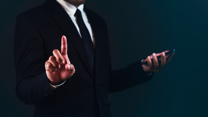 Businessman is using smartphone and pointing or touching for choose something against dark blue background.