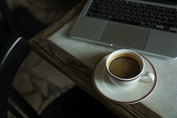A cup of coffee on a table near a laptop in a cafe